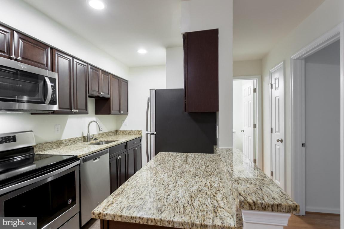8110 Colony Point Road, Unit K Springfield, VA 22152 - Photo 14 of 30 a kitchen with stainless steel appliances granite countertop a stove refrigerator and microwave