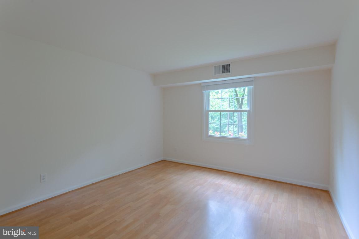 8110 Colony Point Road, Unit K Springfield, VA 22152 - Photo 17 of 30 an empty room with wooden floor and windows
