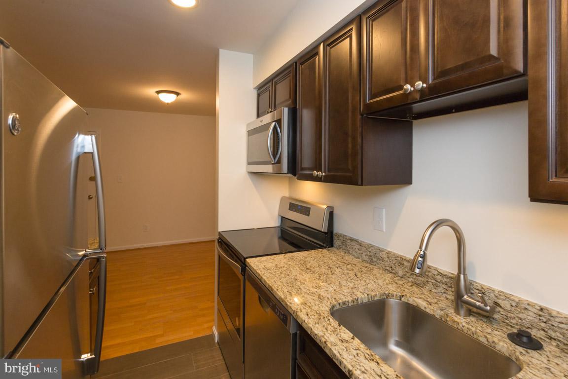 8110 Colony Point Road, Unit K Springfield, VA 22152 - Photo 9 of 30 a kitchen with stainless steel appliances granite countertop a sink a stove and a wooden cabinets