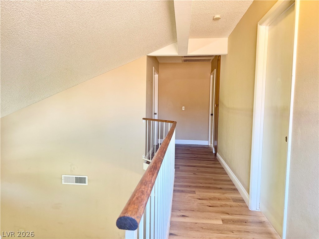 135 Primero Way Henderson, NV 89074 - Photo 8 of 15 An inviting upper-level hallway with beautiful wood flooring and natural tones.