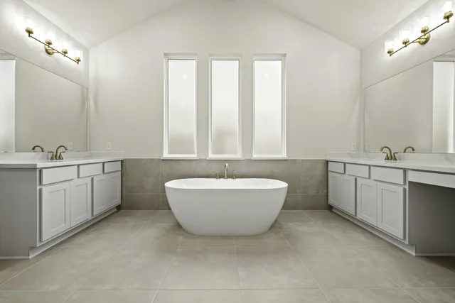 a bathroom with a double vanity sink a bathtub and mirror