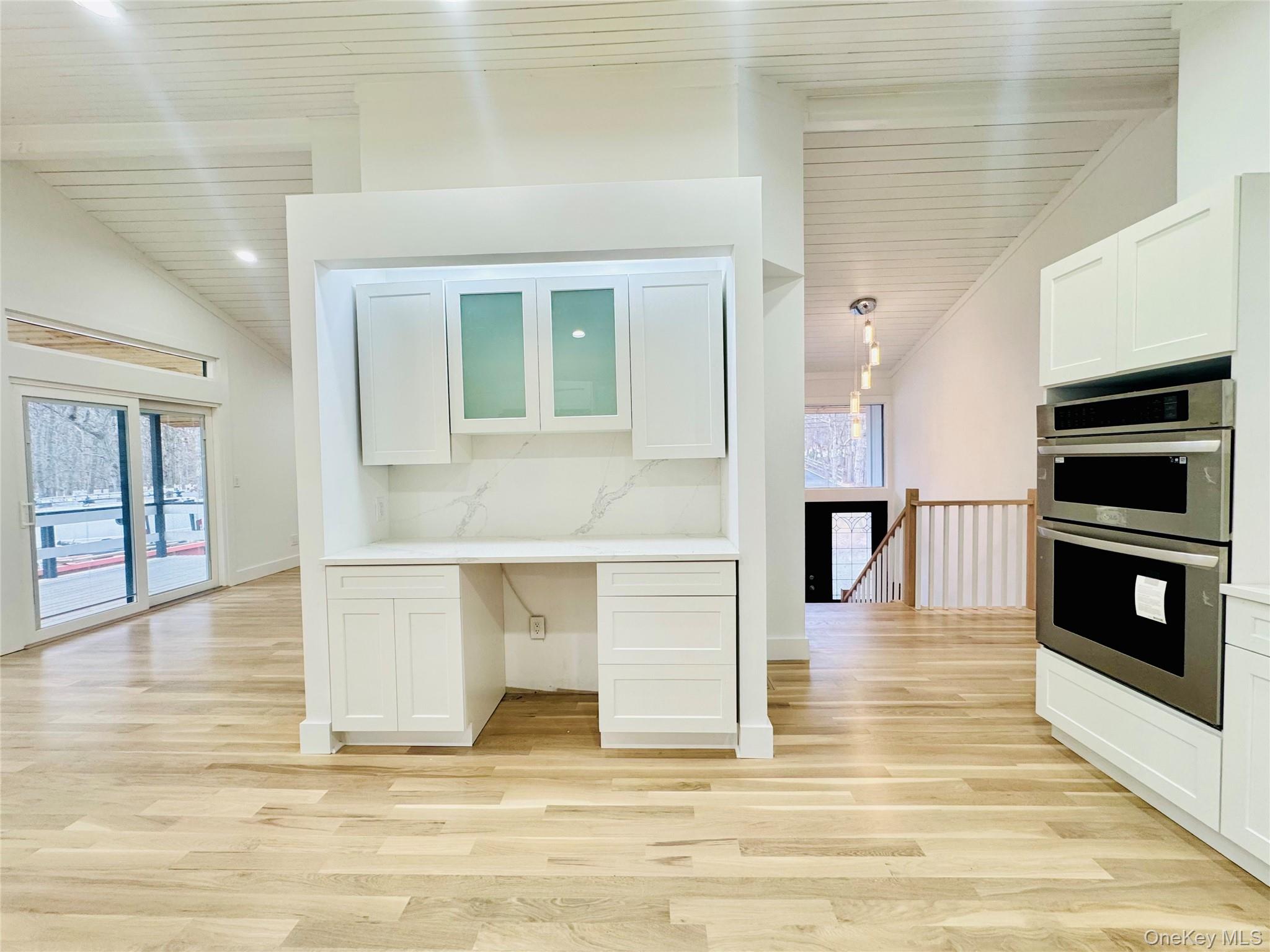 105 Old Riverhead Road Hampton Bays, NY 11946 - Photo 2 of 18 Kitchen with glass insert cabinets, white cabinetry, double oven, lofted ceiling, and built in desk