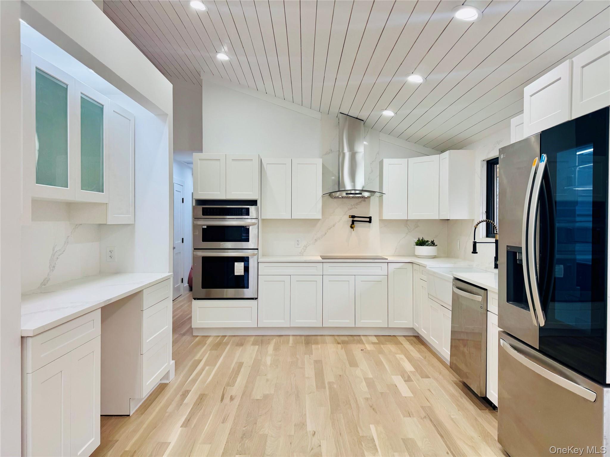 105 Old Riverhead Road Hampton Bays, NY 11946 - Photo 3 of 18 Kitchen featuring lofted ceiling, stainless steel appliances, decorative backsplash, white cabinetry, and wood ceiling