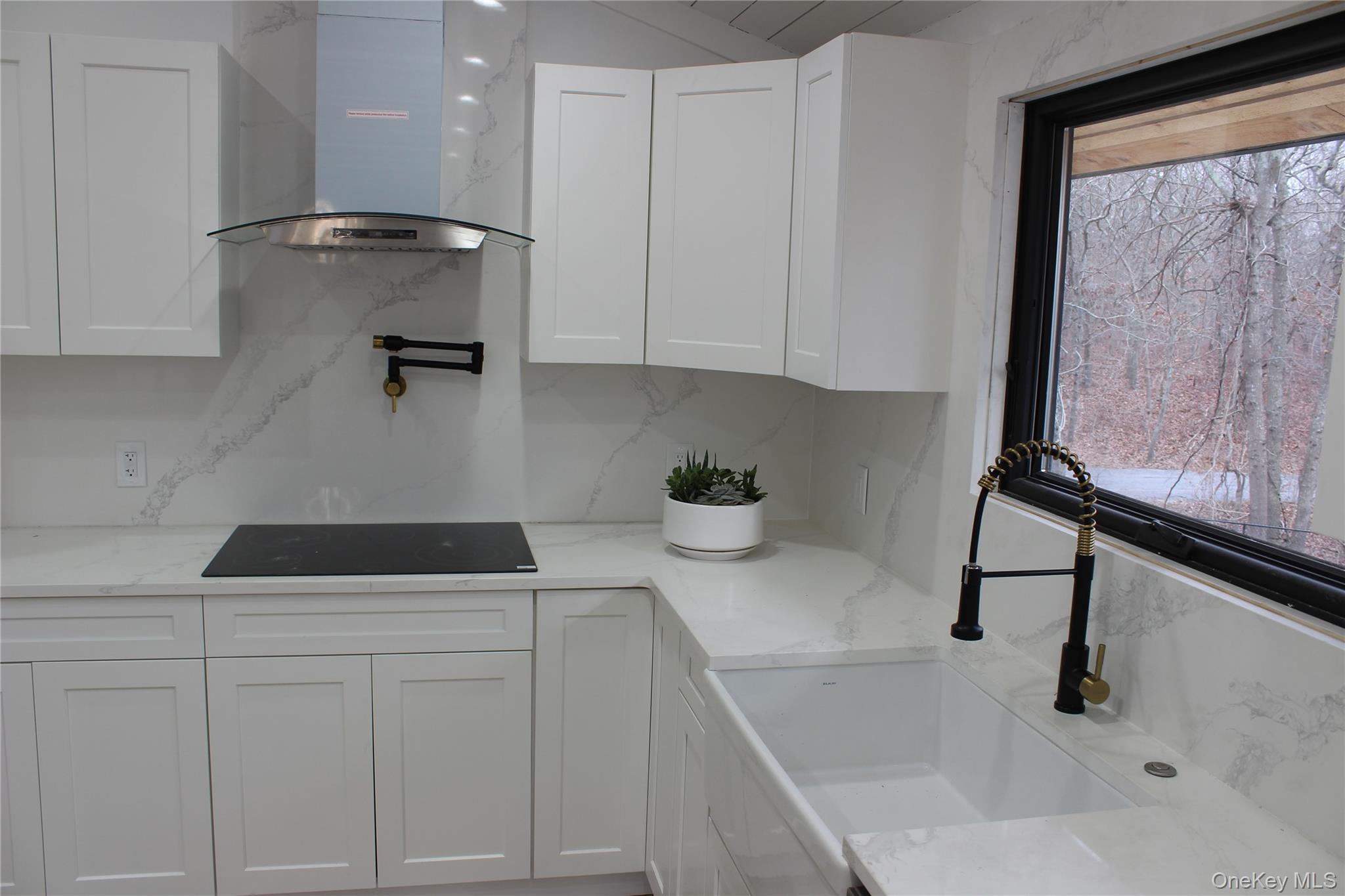 105 Old Riverhead Road Hampton Bays, NY 11946 - Photo 6 of 18 Kitchen featuring extractor fan, white cabinetry, and light stone countertops