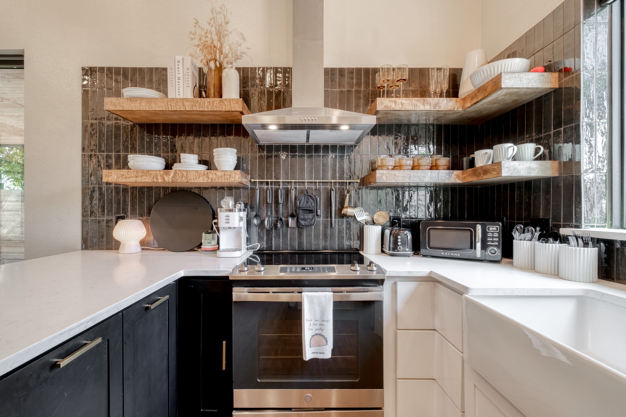 1904 East 16th Street, Unit 2 Austin, TX 78702 - Photo 11 of 20 Modern kitchen featuring white countertops, dark vertical tile backsplash, stainless steel range with hood, and open shelving