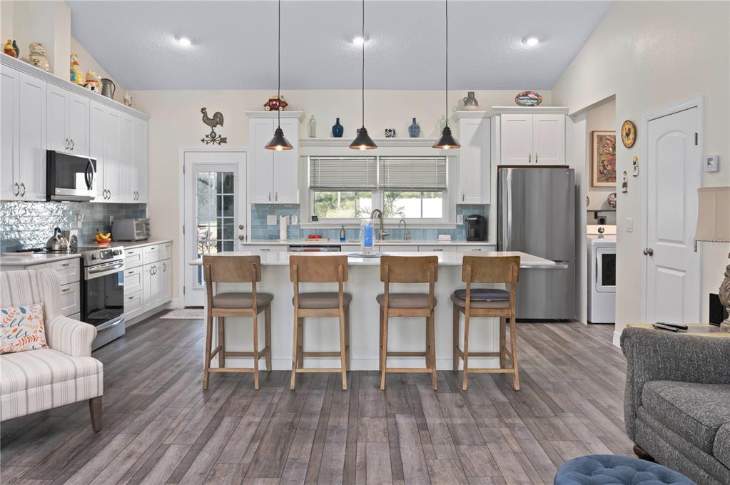 1212 Reynolds Road De Leon Springs, FL 32130 - Photo 11 of 32 a kitchen with stainless steel appliances granite countertop a refrigerator a stove top oven a sink dishwasher and white cabinets with wooden floor