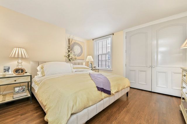 a bed sitting in a spacious bedroom next to a window and a wooden floor