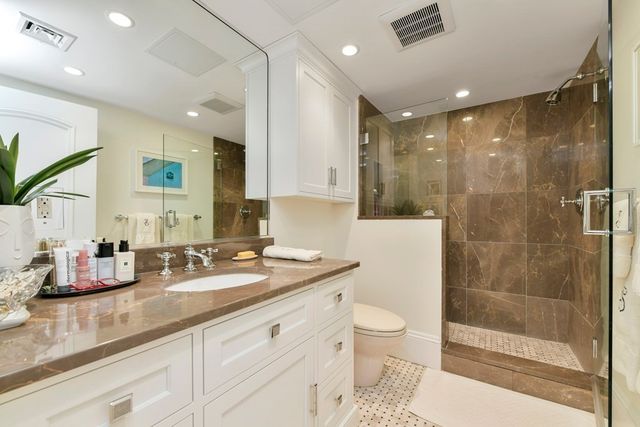a bathroom with a granite countertop sink a toilet a mirror and shower
