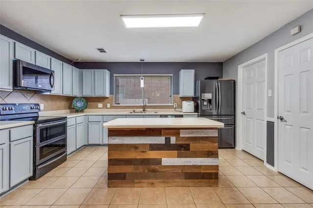 a large kitchen with stainless steel appliances granite countertop a stove oven and a refrigerator