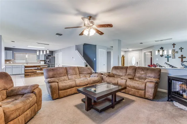 a living room with furniture kitchen view and a chandelier