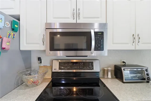 a kitchen with microwave a stove and cabinets