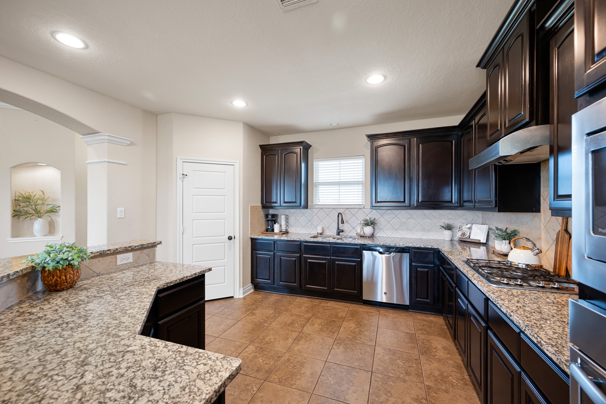 8131 Brinkmeyer Road Needville, TX 77461 - Photo 12 of 34 This modern kitchen features dark wood cabinets, granite countertops, and stainless steel appliances.