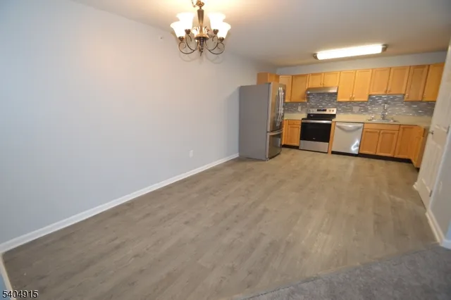 a view of a kitchen with a sink and dishwasher a refrigerator with wooden floor