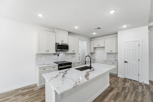 a large white kitchen with sink stove and refrigerator