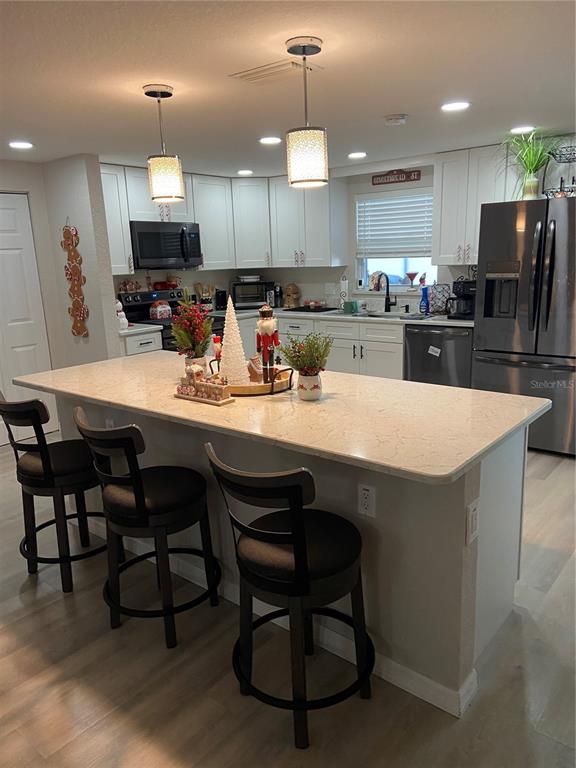 5343 Bluepoint Drive Port Richey, FL 34668 - Photo 25 of 28 a kitchen with a dining table chairs stainless steel appliances and cabinets