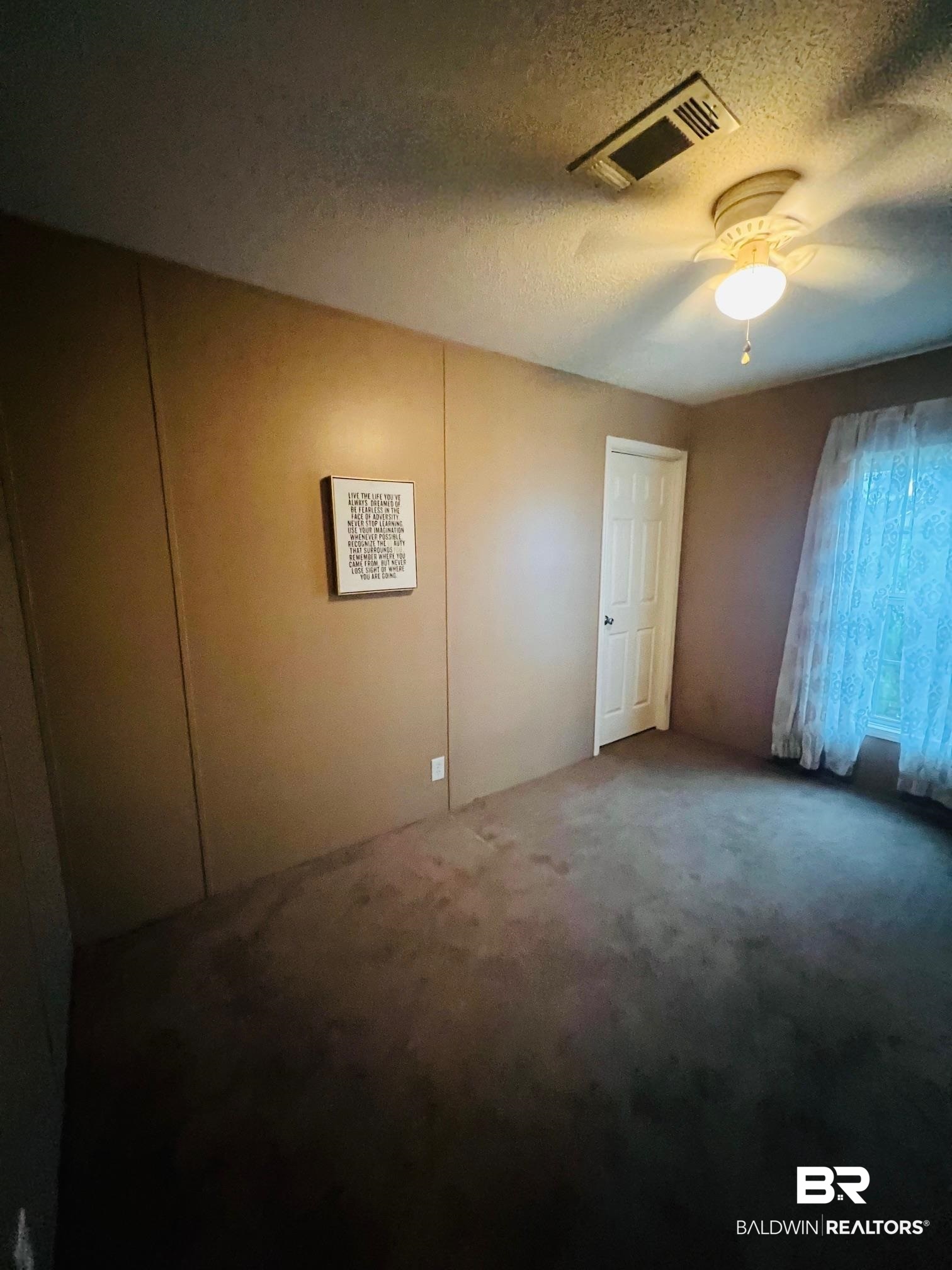 1985 Ridgewood Drive South Lillian, AL 36549 - Photo 9 of 40 Empty room featuring a textured ceiling, ceiling fan, and carpet
