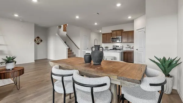 a kitchen with kitchen island a dining table chairs stainless steel appliances and cabinets