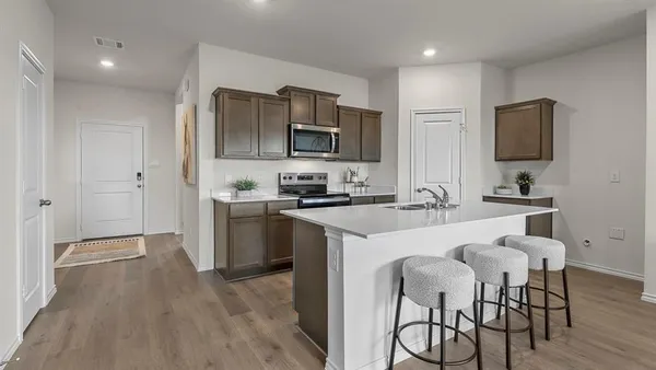a kitchen with a table chairs microwave and cabinets