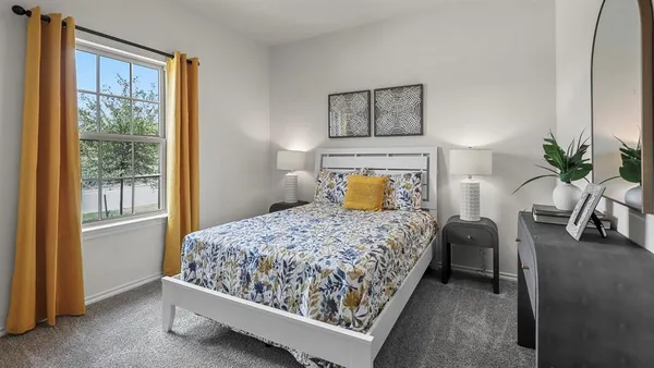a bedroom with a bed and potted plant next to a window