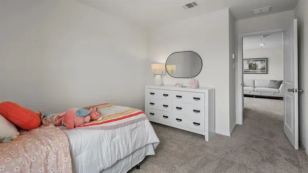 a bedroom with a bed a mirror and a lamp on dresser