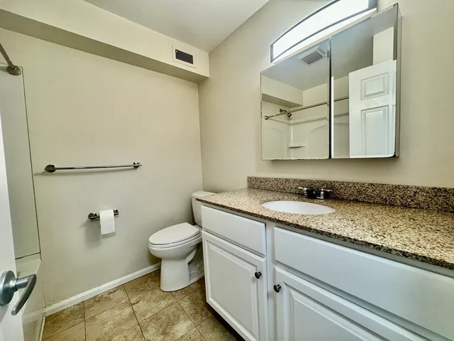 a bathroom with a granite countertop sink toilet and a mirror