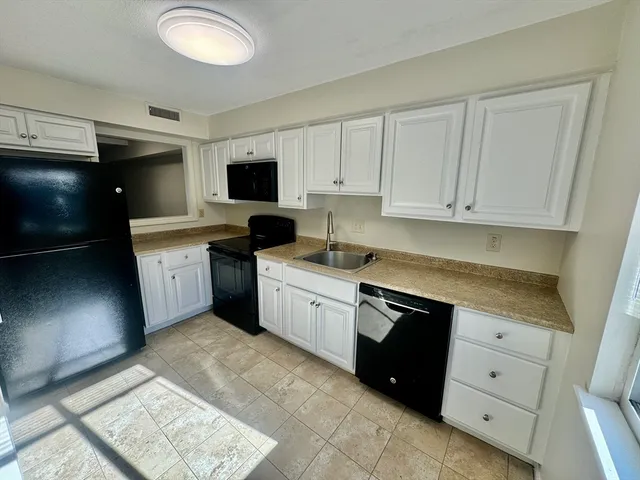 a kitchen with granite countertop white cabinets and stainless steel appliances