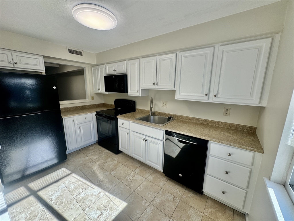 13 Beal's Cove Road, Unit E Hingham, MA 02043 - Photo 2 of 20 a kitchen with granite countertop white cabinets and stainless steel appliances