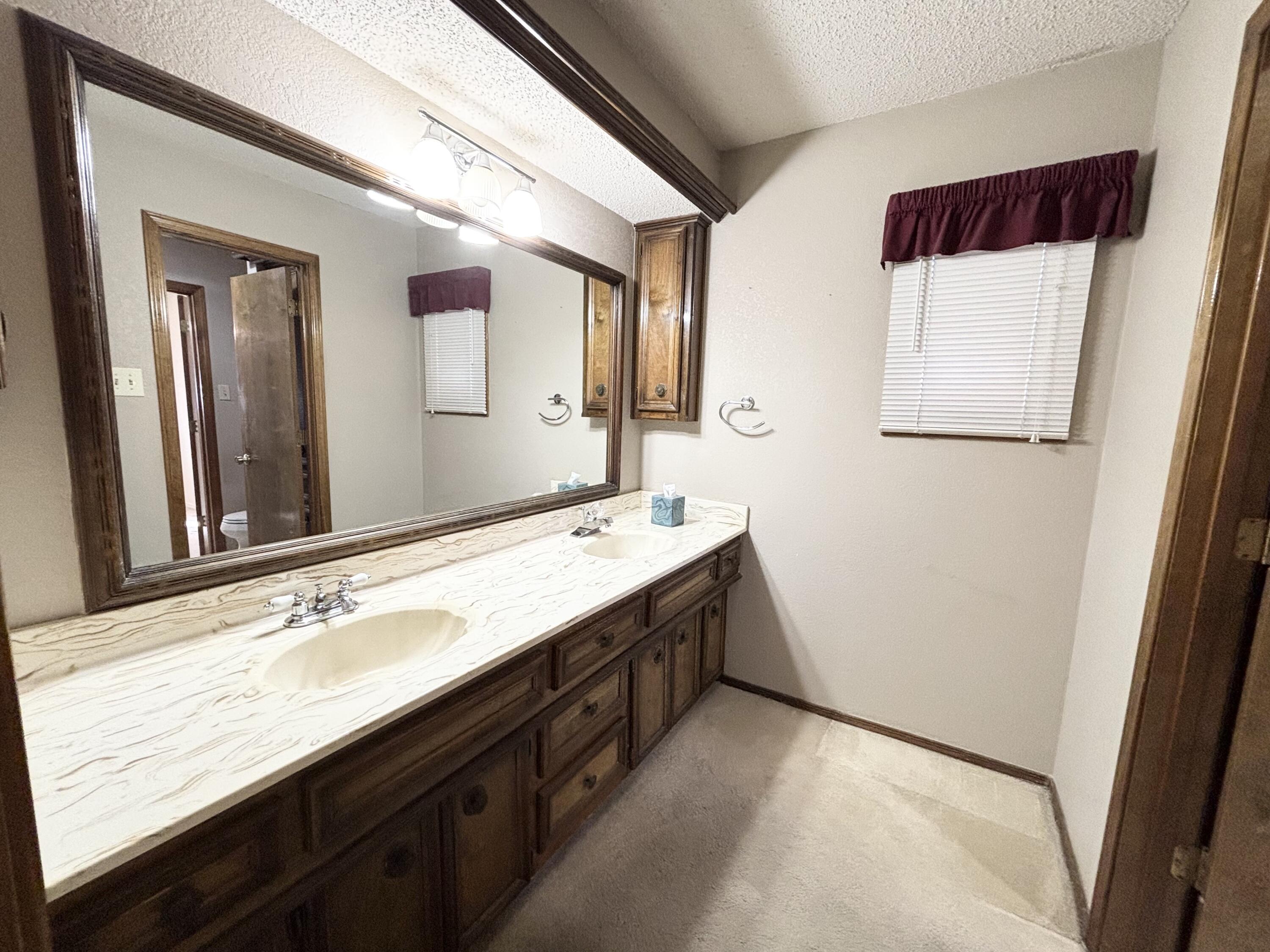 4913 62nd Street Lubbock, TX 79414 - Photo 16 of 22 a bathroom with a sink and a mirror