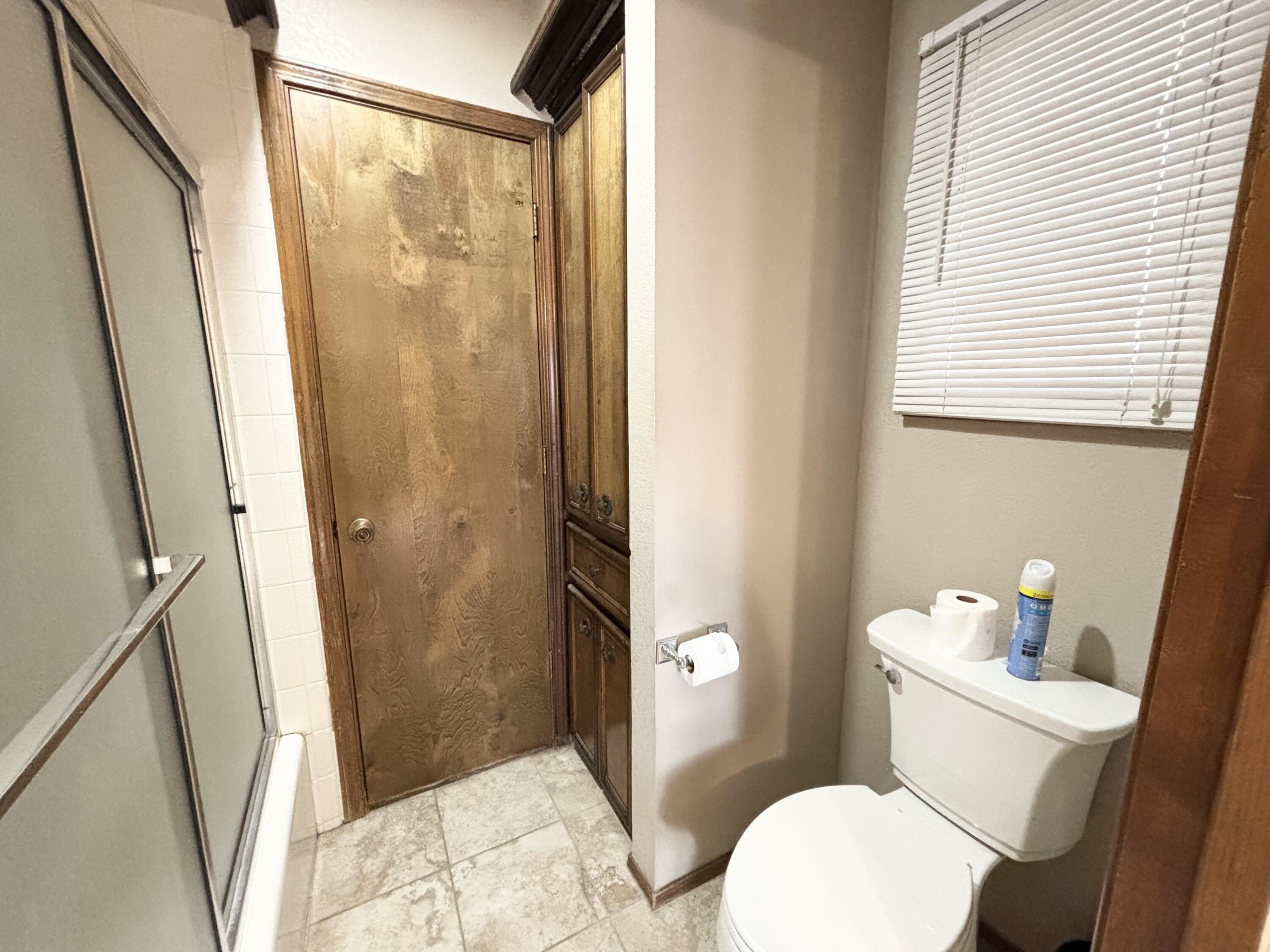 4913 62nd Street Lubbock, TX 79414 - Photo 17 of 22 a white toilet sitting next to a bathroom sink and a shower
