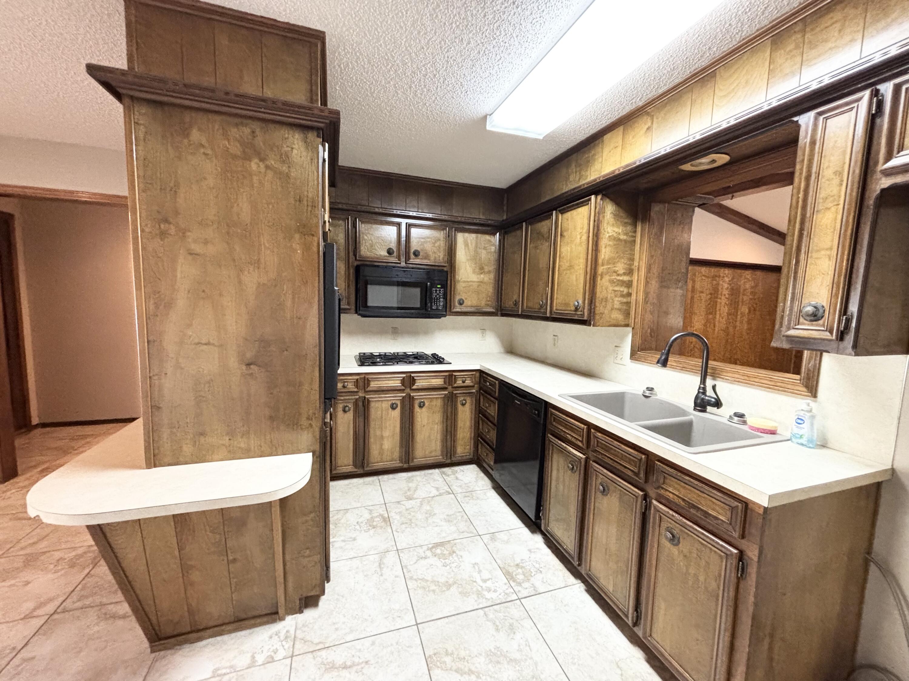 4913 62nd Street Lubbock, TX 79414 - Photo 6 of 22 a kitchen with a sink a refrigerator and cabinets