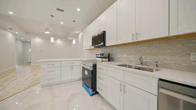 a kitchen with a sink dishwasher and white cabinets with wooden floor
