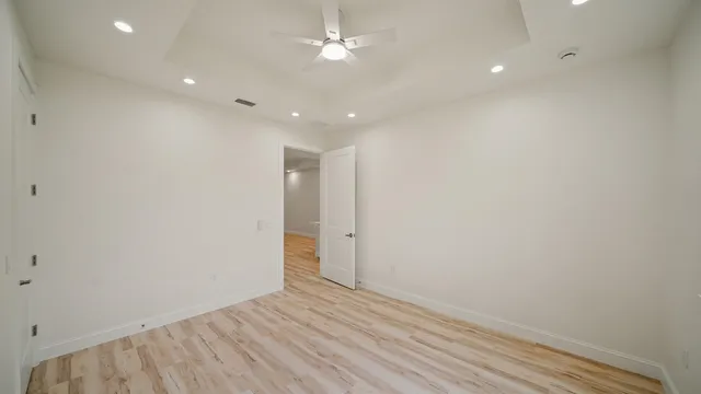 an empty room with wooden floor and fan