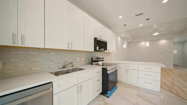 a kitchen with a sink dishwasher and white cabinets with wooden floor