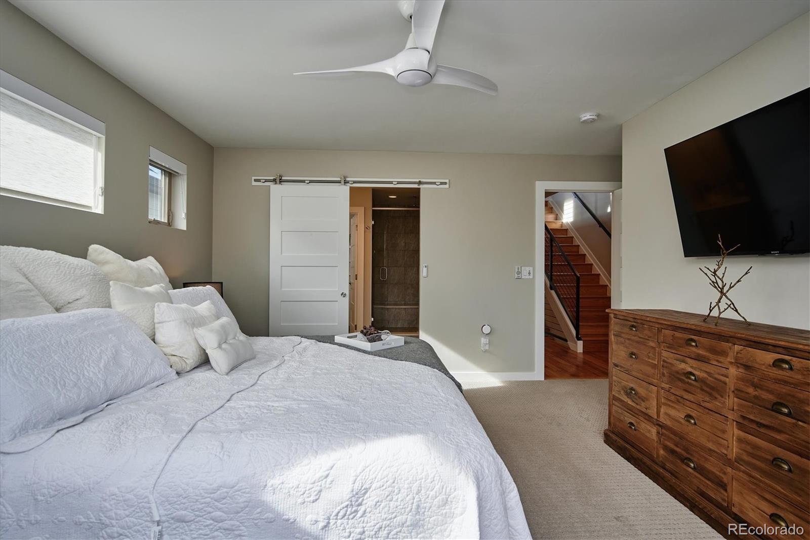 4583 Utica Street Denver, CO 80212 - Photo 17 of 40 a bedroom with a bed and a flat tv screen on wall