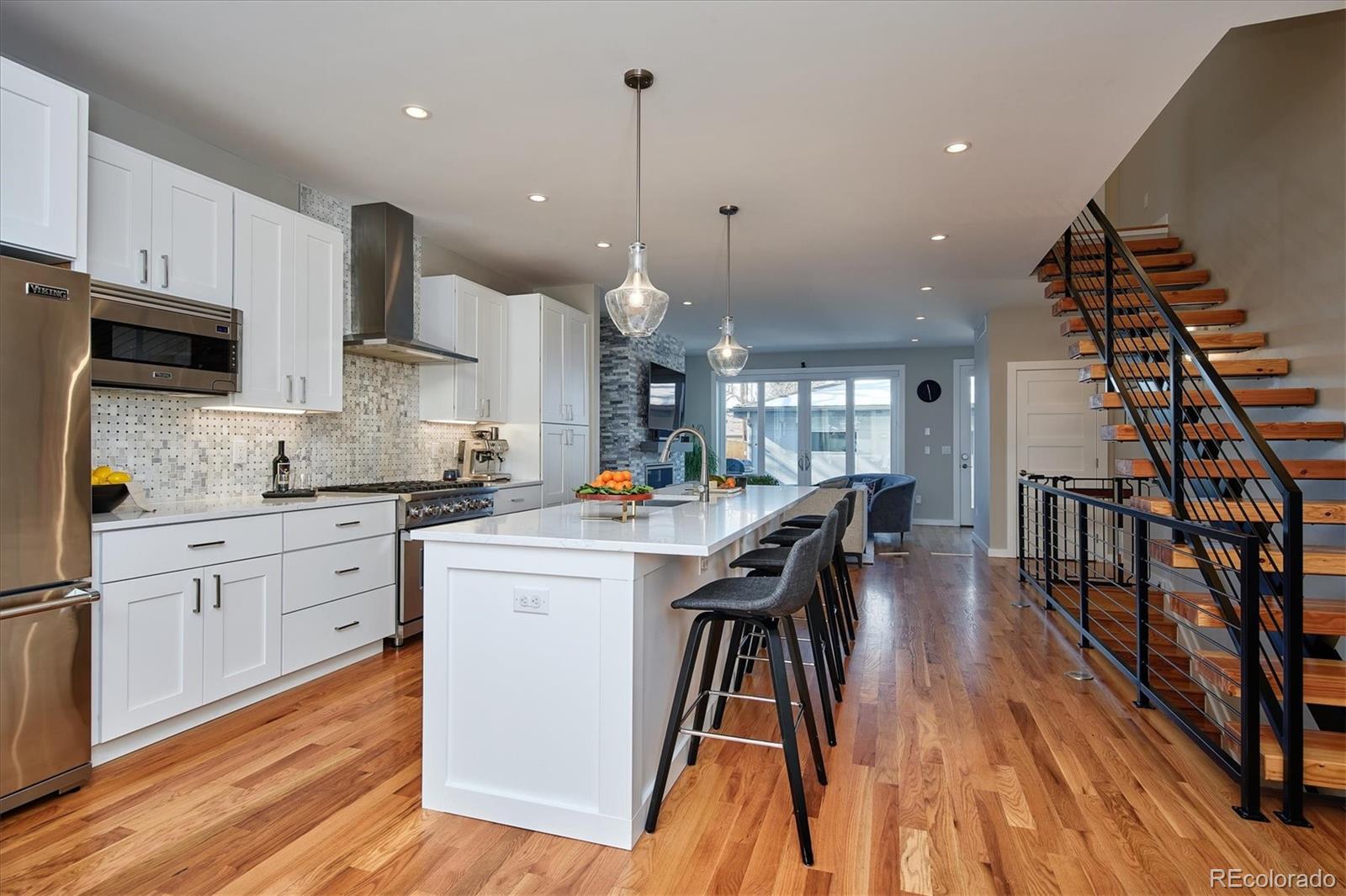 4583 Utica Street Denver, CO 80212 - Photo 6 of 40 a kitchen with stainless steel appliances kitchen island granite countertop a stove top oven a sink a dining table and chairs with wooden floor