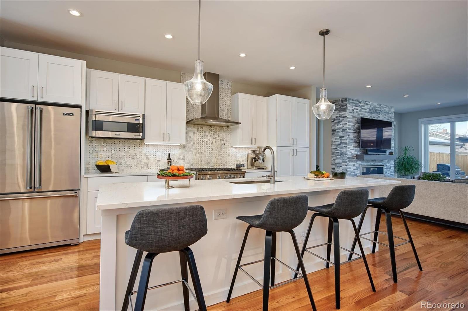 4583 Utica Street Denver, CO 80212 - Photo 8 of 40 a kitchen with stainless steel appliances kitchen island a refrigerator and a wooden floor