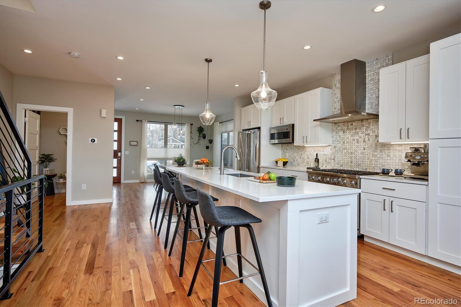 4583 Utica Street Denver, CO 80212 - Photo 9 of 40 a kitchen with stainless steel appliances kitchen island granite countertop a stove a sink a refrigerator a center island and a wooden floor