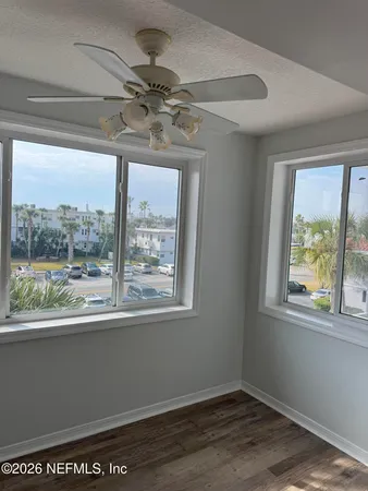 a view of empty room with wooden floor and fan