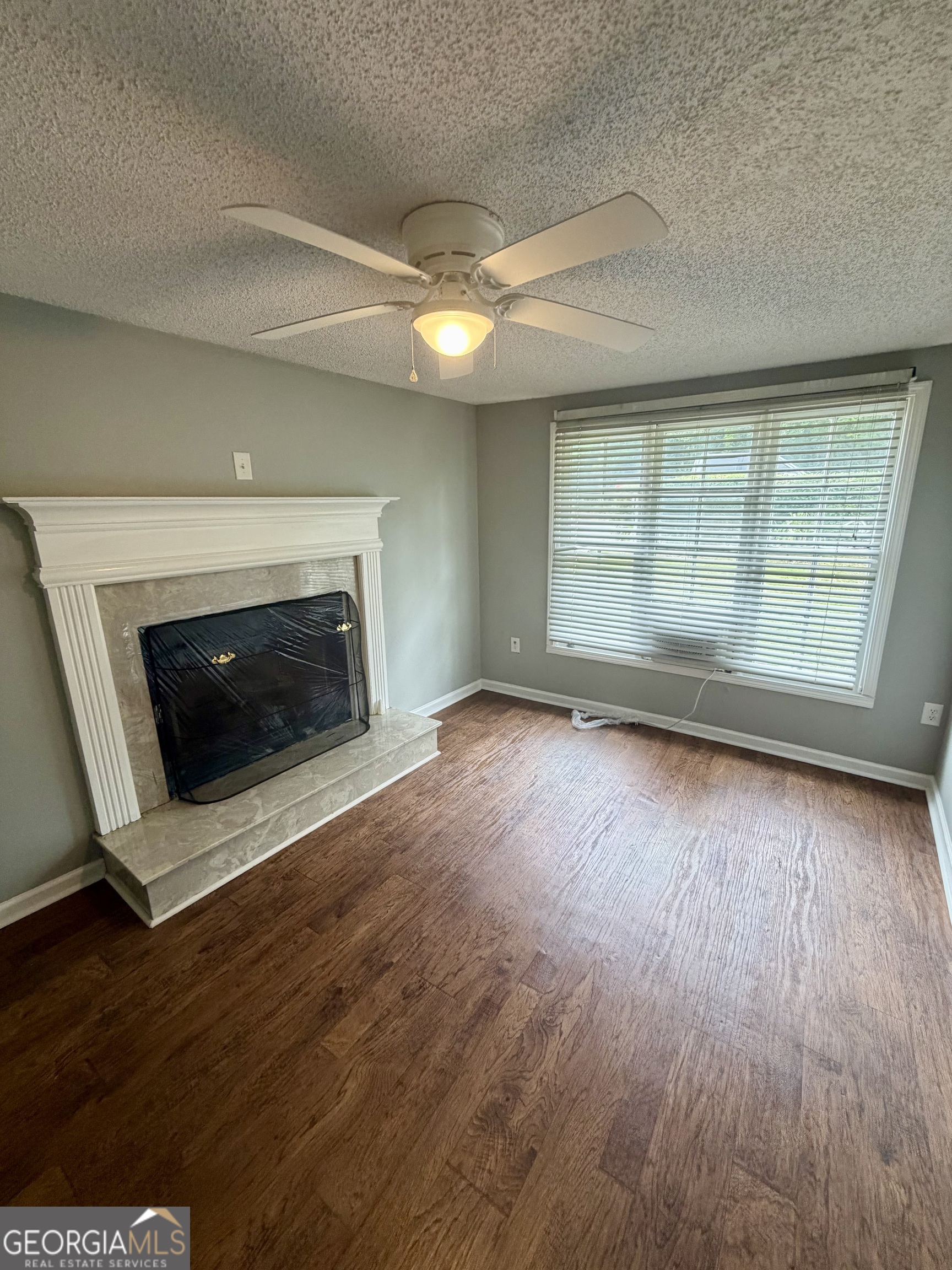 666 Woolfolk Street Macon, GA 31217 - Photo 13 of 60 an empty room with wooden floor fireplace and windows
