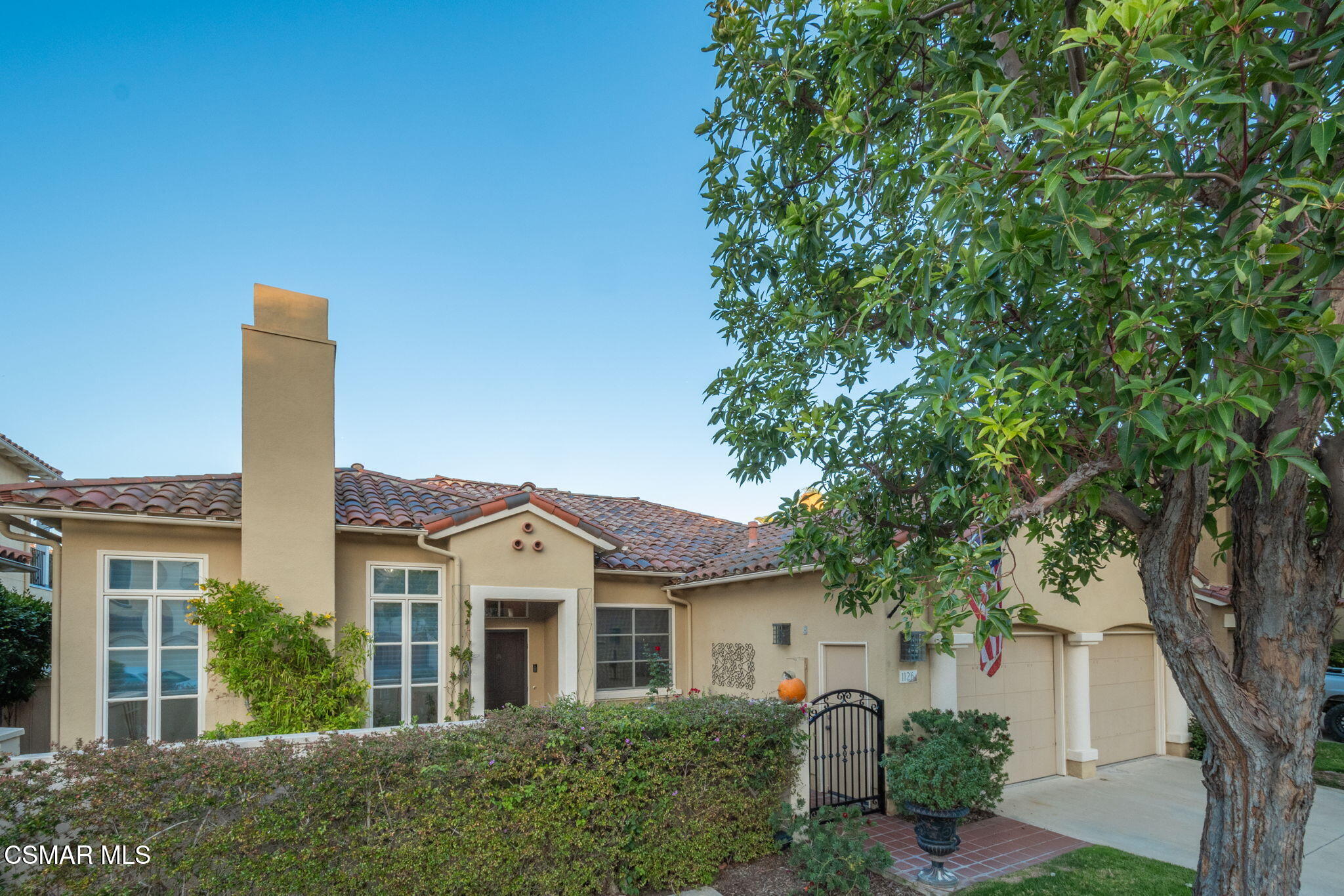 a front view of a house with a garden and tree