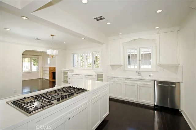 a large white kitchen with stainless steel appliances granite countertop a stove and a sink