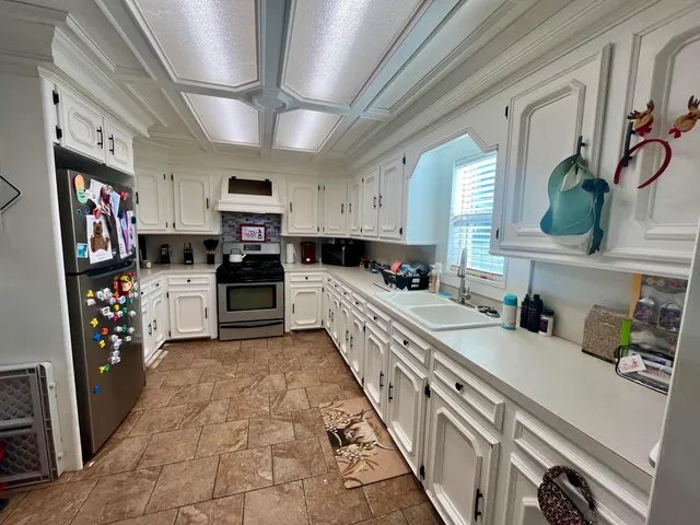 a kitchen with stainless steel appliances granite countertop a refrigerator a stove top oven a sink and dishwasher