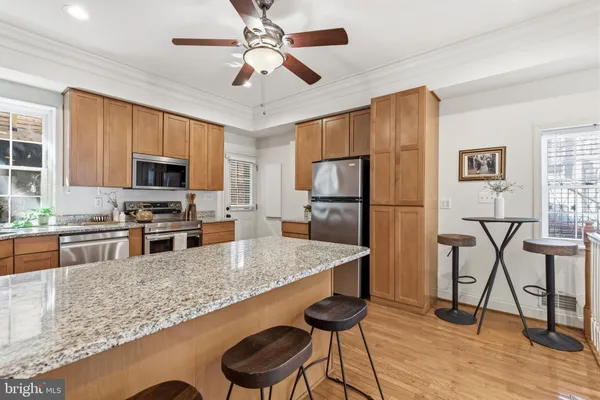 a kitchen with stainless steel appliances granite countertop a refrigerator a stove top oven a sink dishwasher a dining table and chairs with wooden floor
