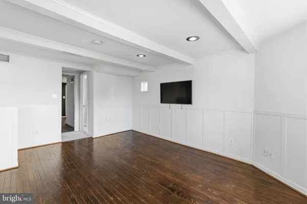 a view of an empty room with wooden floor and windows