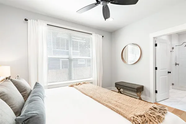 a bedroom with a bed a dresser and a large window