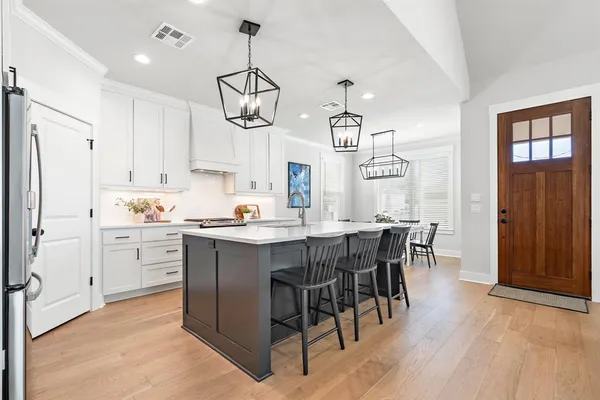 a kitchen with a refrigerator a sink dishwasher a dining table and chairs with wooden floor