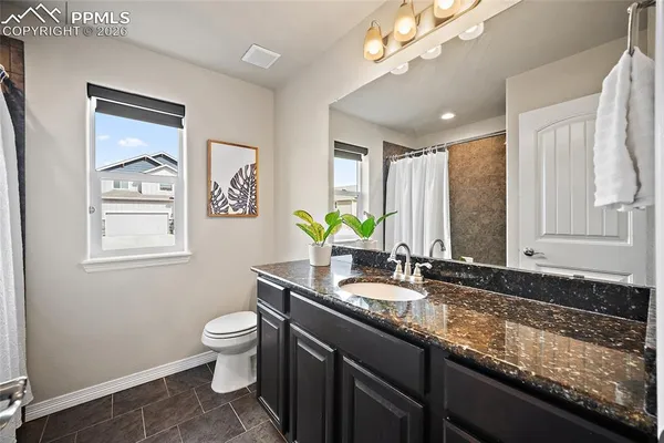 a bathroom with a granite countertop sink a toilet and a mirror
