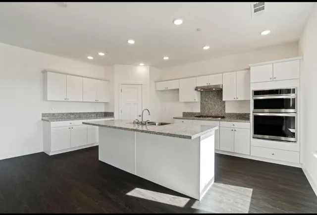 a kitchen with granite countertop white cabinets and stainless steel appliances