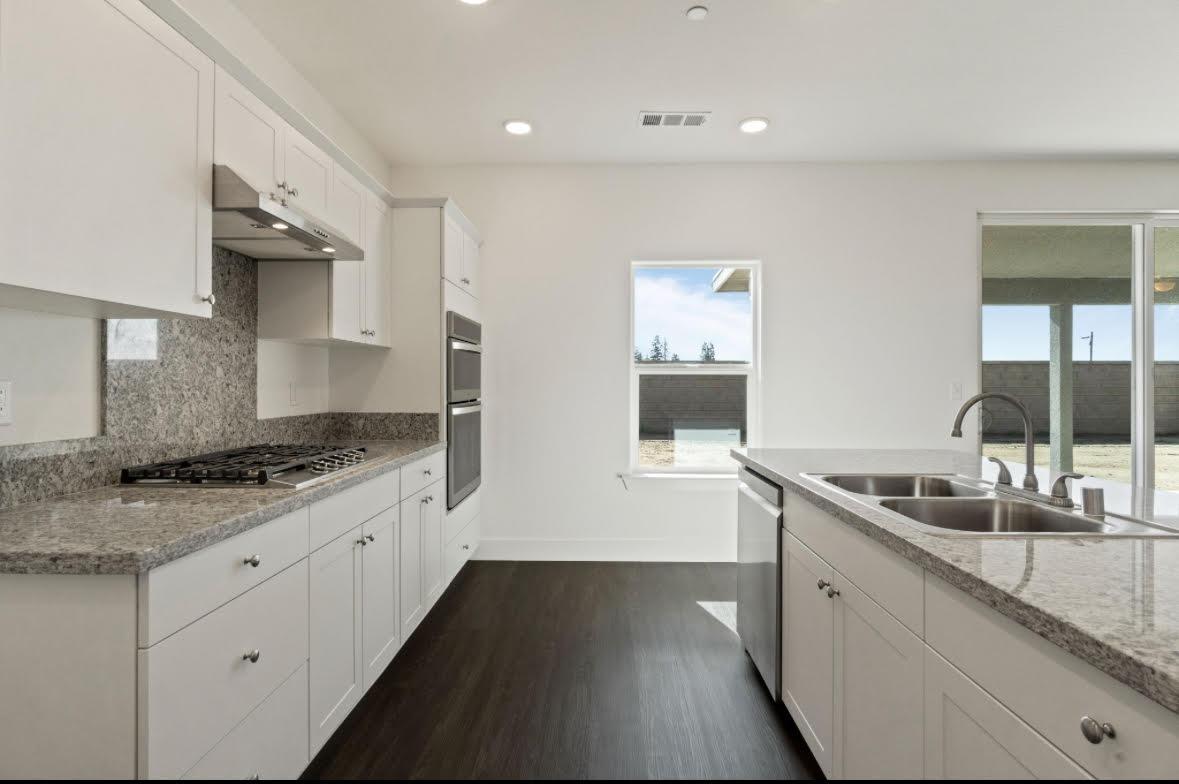 1207 Via Valencia Madera, CA 93637 - Photo 5 of 10 a kitchen with granite countertop a sink and a stove