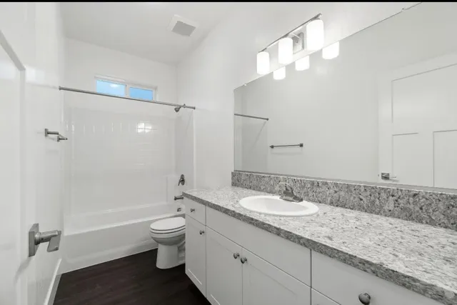 a bathroom with a granite countertop sink a toilet and shower